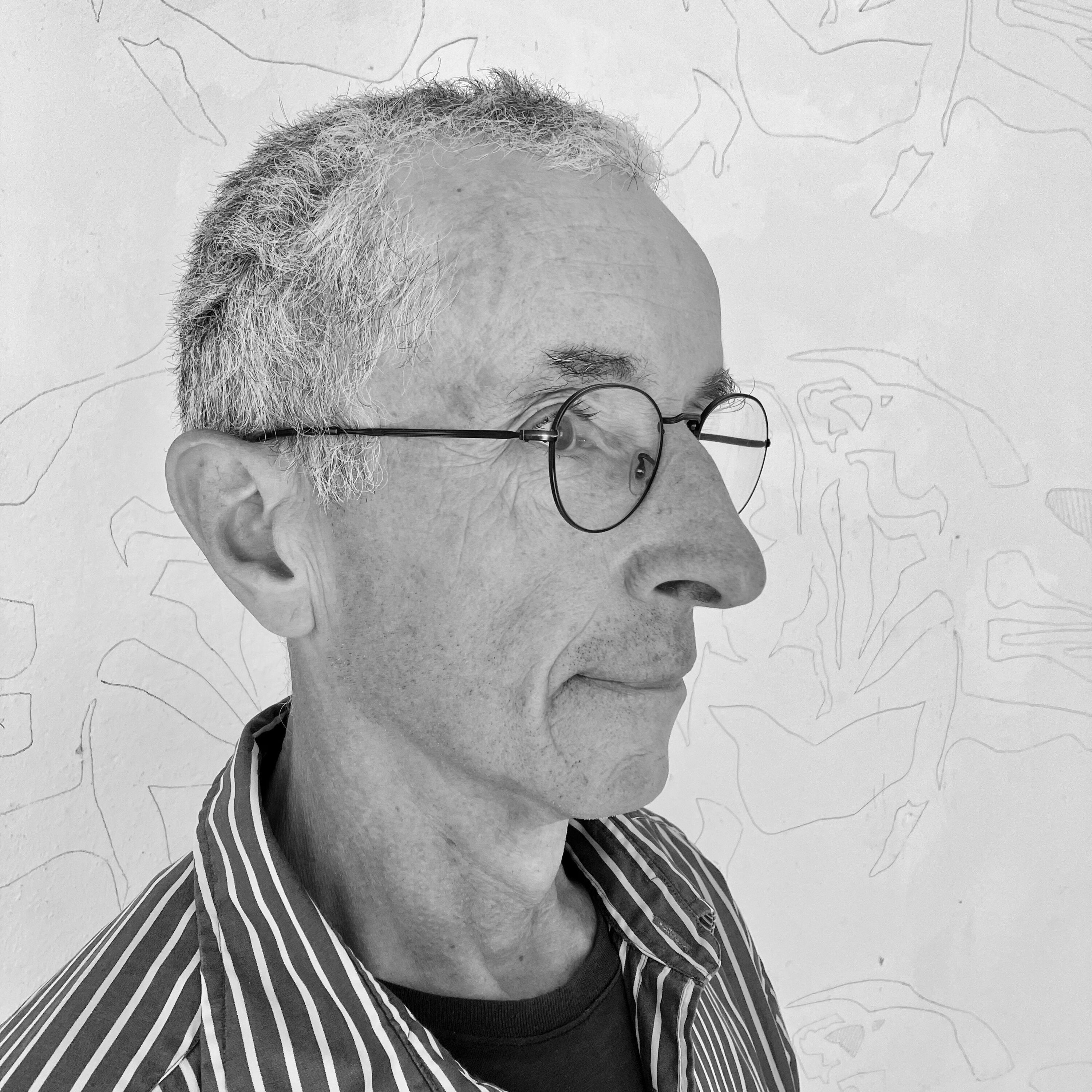 Schwarz-Weiß-Foto des Künstlers Rainer Michel in der schrägen Seitenansicht mit einem gestreiften Hemd und Brille