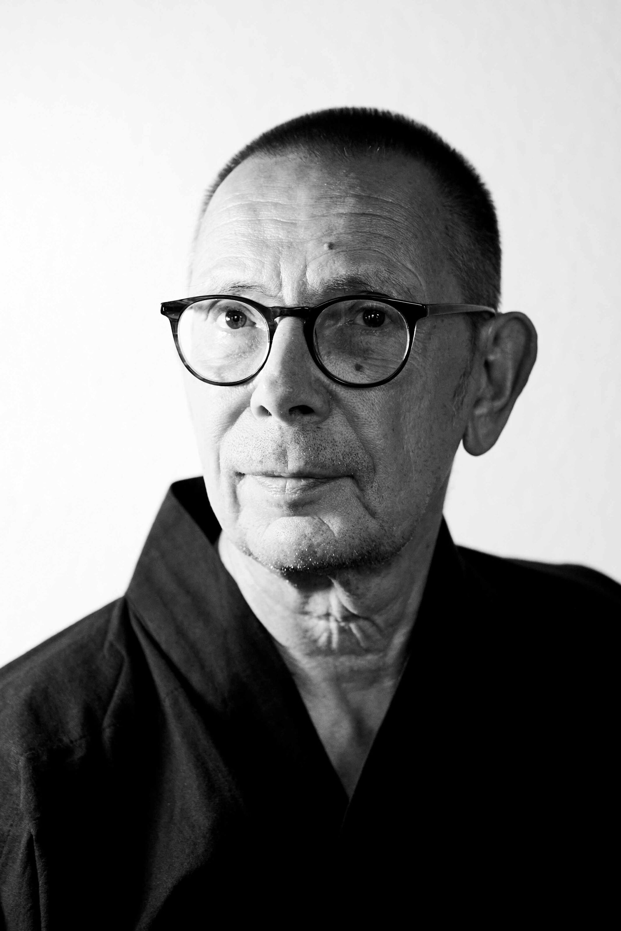 Schwarz-Weiß-Foto des Künstlers Thomas Schmitt-Schech mit einem schwarzen Oberteil, kurzem Haar und einer Brille